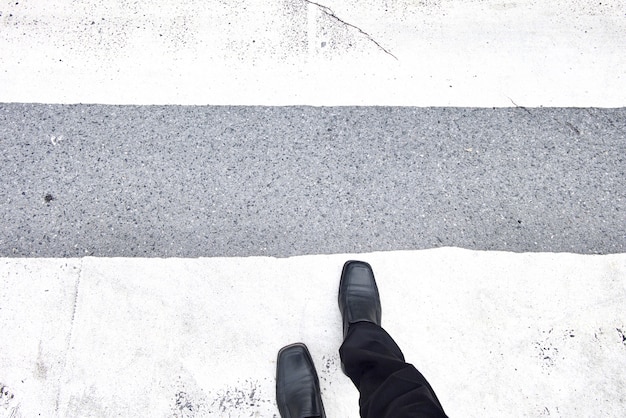 Businessman walking across the crosswalk. Black leather shoes and black slacks. 