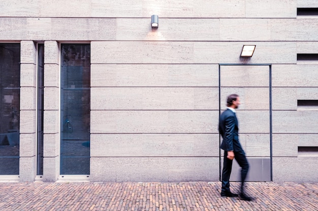 Photo businessman walking by wall