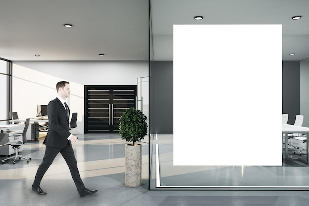 Foto uomo d'affari che entra in una sala conferenze con un poster vuoto, un tavolo da riunione e una parete di vetro, un luogo di lavoro e uno stile di vita