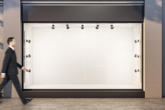 Businessman walking down street near shop window with blank poster