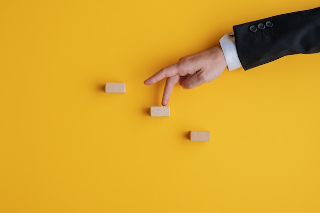 Businessman walking his fingers up the steps made of wooden blocks