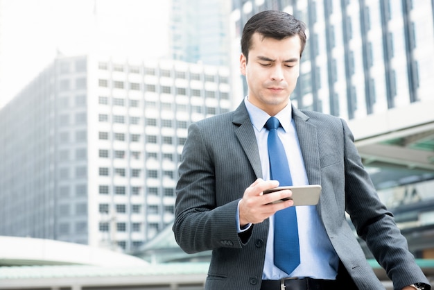 Businessman walking and looking at smartphone 