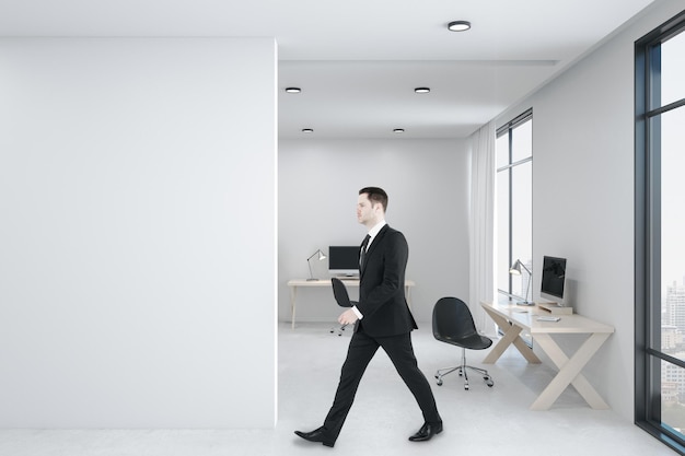 Businessman walking in office room with personal computer
