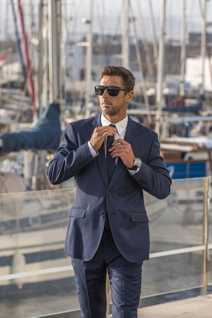 Businessman walking in port and adjusting tie