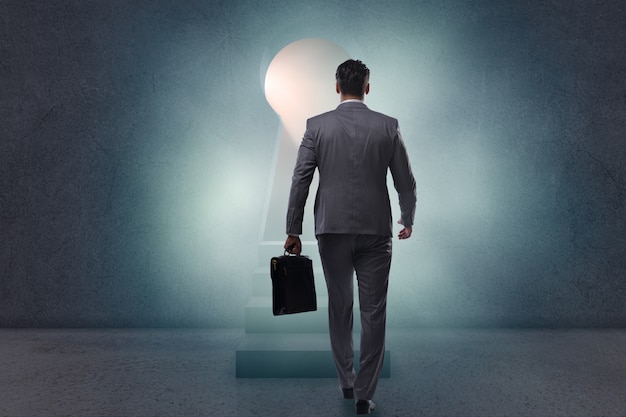 Businessman walking towards light from keyhole