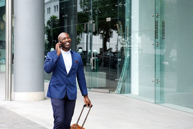 Businessman walking with a suitcase and talking on phone