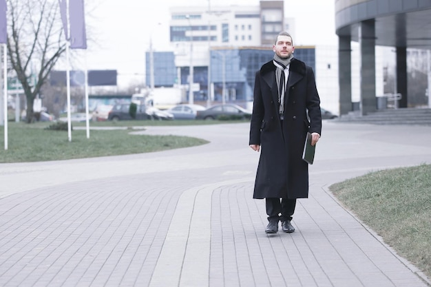 Businessman in warm clothes walking down the street of the\
city