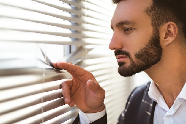 The businessman watching through the blinds