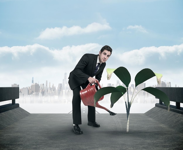 Photo businessman watering with red can against cityscape on the horizon