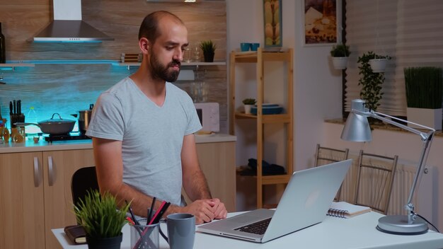 Businessman waving during video conference while working from home at night. employee using modern technology at midnight doing overtime for job, business, career, network, lifestyle ,wireless.