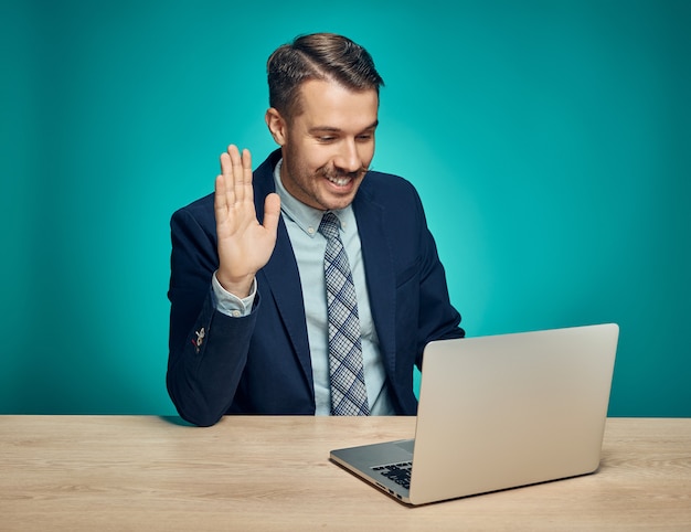 Businessman waving at a laptop