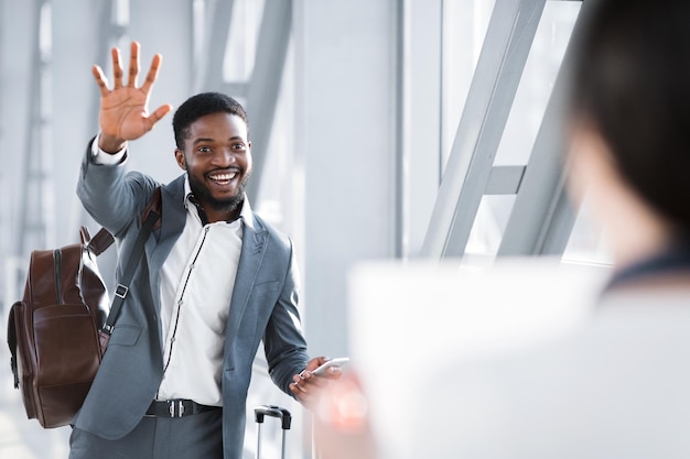 Businessman Waving To Partner Waiting For Him In Airport