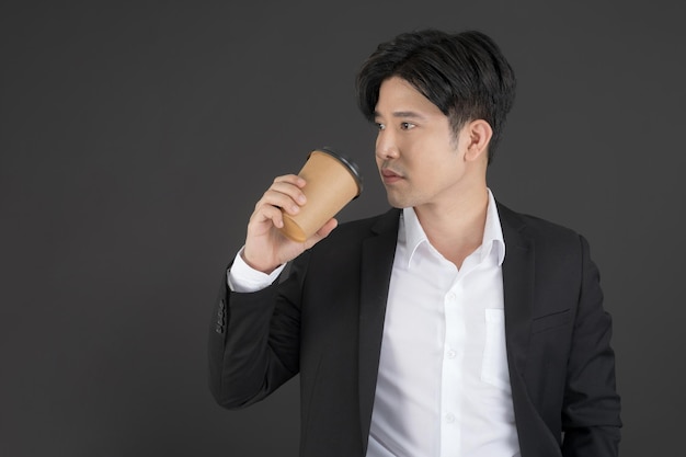 Businessman wearing a black suit standing with a cup of coffee