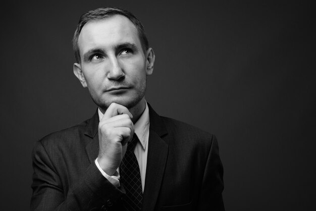 businessman wearing suit against gray wall in black and white