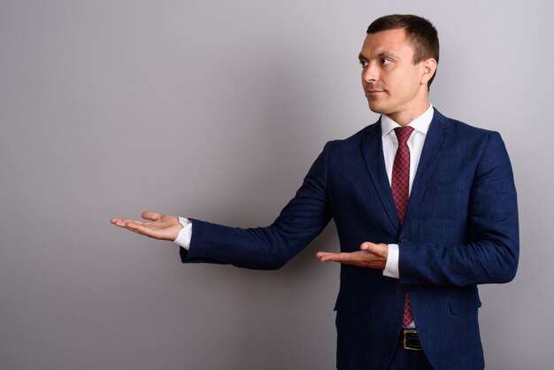 Businessman wearing suit against gray wall