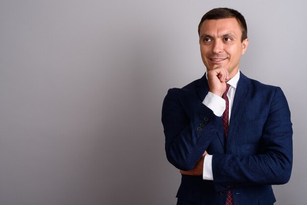 Businessman wearing suit against gray wall