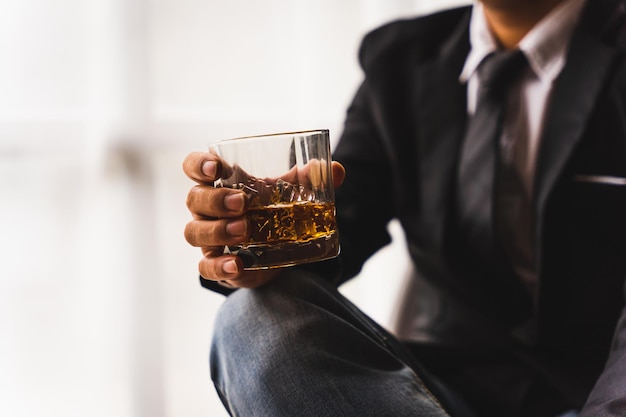 Businessman wearing suit sits in the luxury bar in gentlemen club and drink whiskey