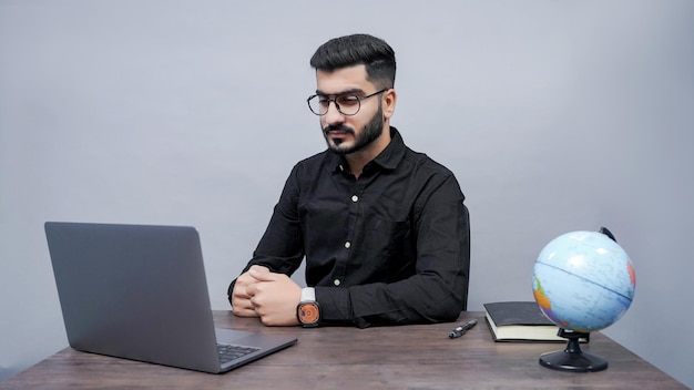 businessman wearing watch with glasess looking in laptop in black shirt indian pakistani model