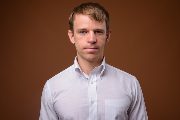 businessman wearing white shirt against brown wall