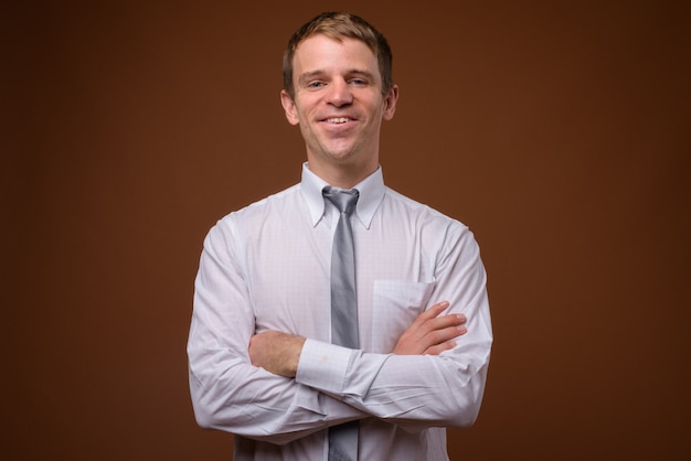 businessman wearing white shirt against brown wall