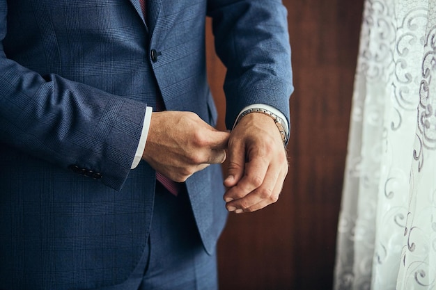 Businessman wears a jacketmale hands closeupgroom getting ready in the morning before wedding ceremony