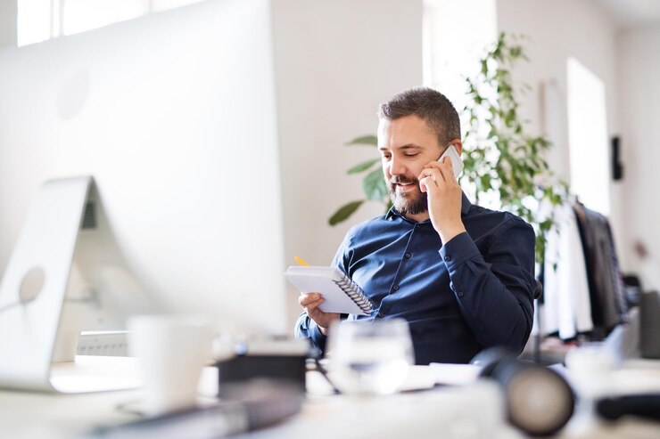 Photo businessman in wheelchair with smartphone in his office