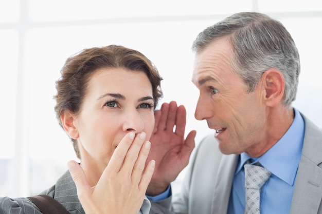 Businessman whispering something to his colleague