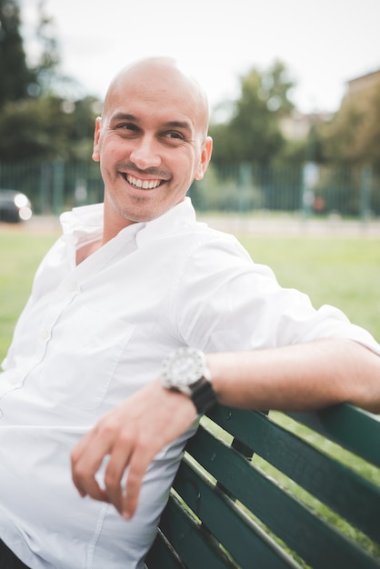 Businessman in white shirt sitting on a bench in a park 