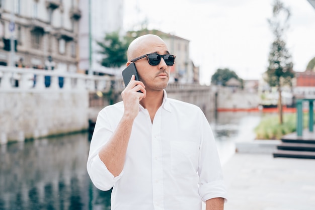 Businessman in white shirt with black sunglasses talking on the phone 