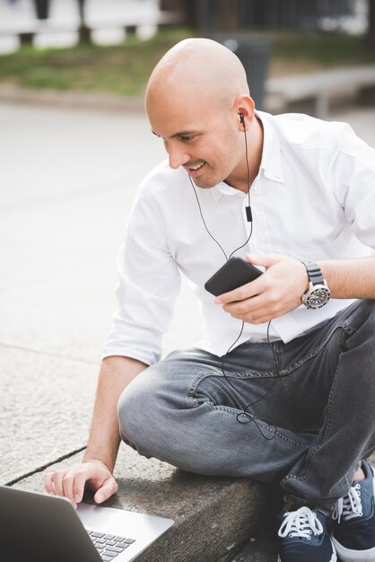 Businessman in white shirt working with laptop sitting on staircase