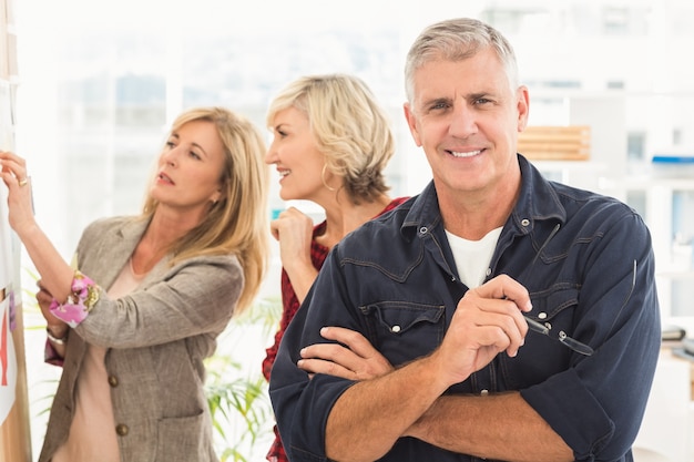 Photo businessman with arms crossed with his team behind