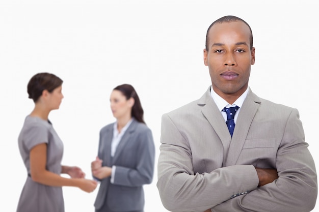 Businessman with arms folded and colleagues behind him