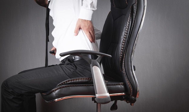 Businessman with back pain sitting in office chair.