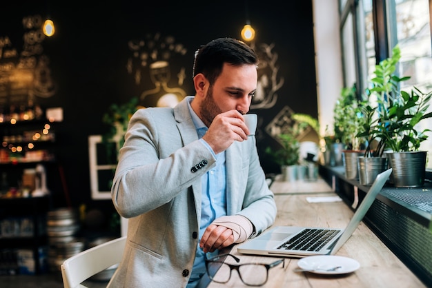 Businessman with bandaged hand drinking coffee in a cafe.