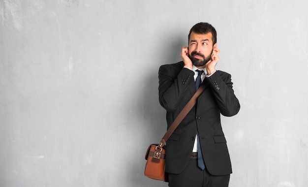 Businessman with beard covering ears with hands. Frustrated expression