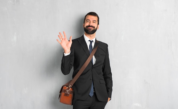 Businessman with beard saluting with hand with happy expression