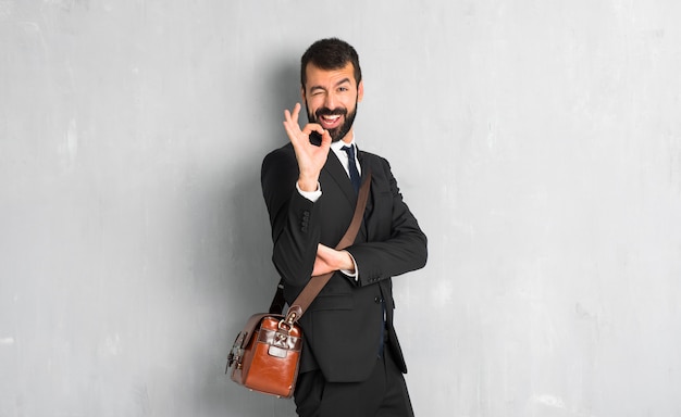 Businessman with beard showing ok sign while winking an eye
