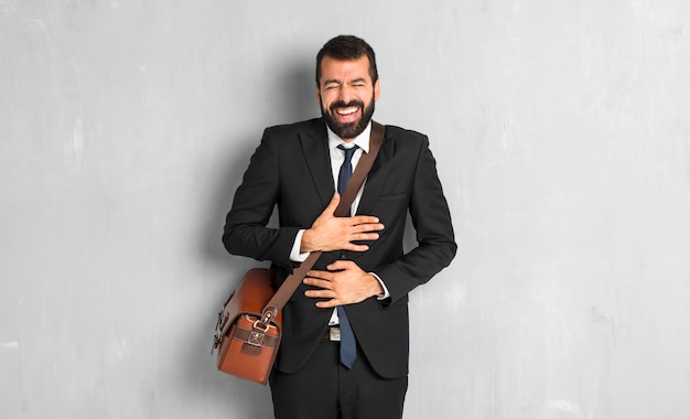 Businessman with beard smiling a lot while putting hands on chest