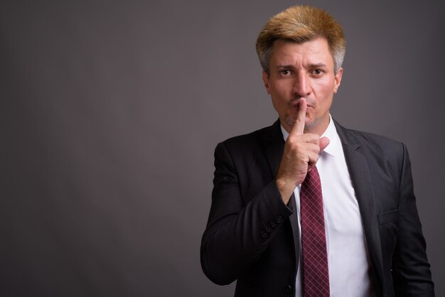 Businessman with blond hair against gray wall