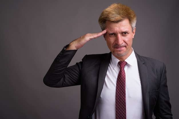 Businessman with blond hair against gray wall