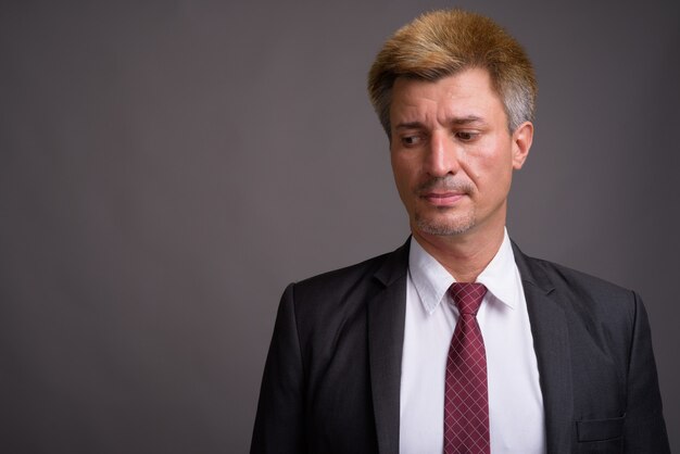 Businessman with blond hair against gray wall