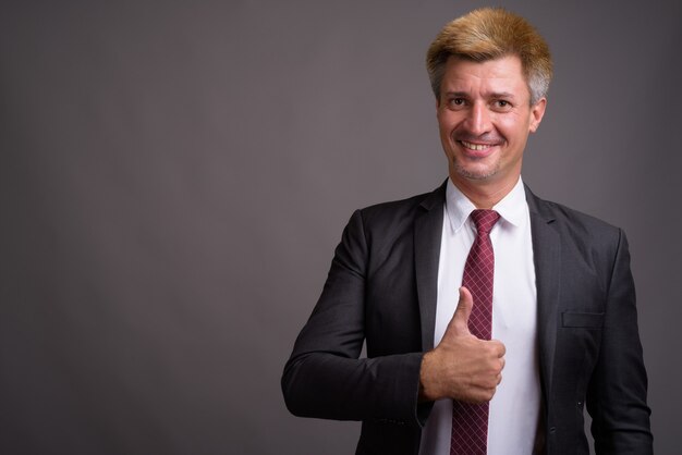 Businessman with blond hair against gray wall