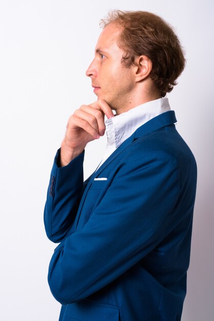 businessman with blond hair wearing blue suit against white space