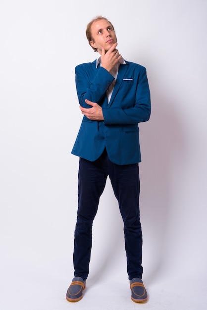  businessman with blond hair wearing blue suit against white wall