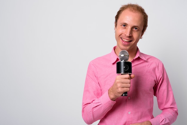 Uomo d'affari con i capelli biondi indossa la camicia rosa contro il muro bianco