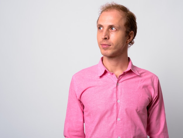  businessman with blond hair wearing pink shirt against white wall