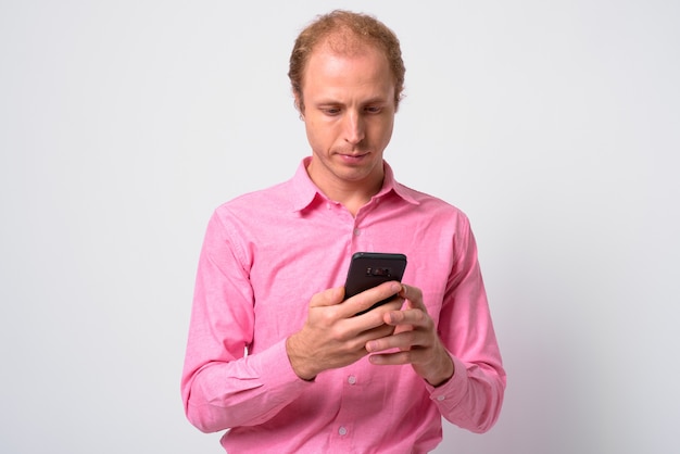  businessman with blond hair wearing pink shirt against white wall