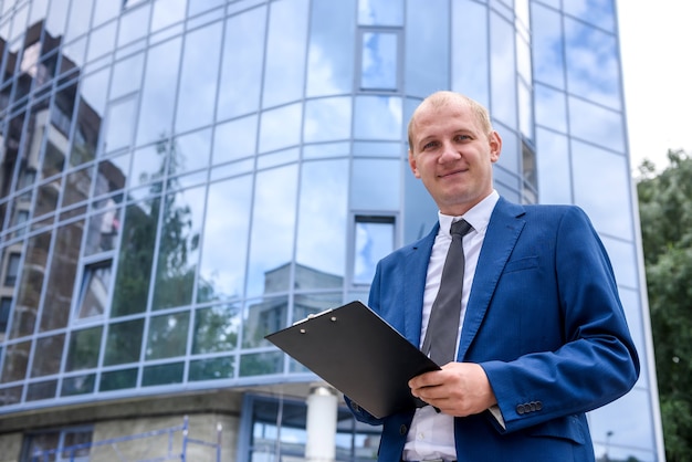 Businessman with clipboard standing against new building