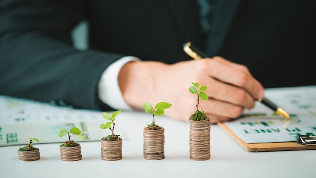 Foto uomo d'affari con un mucchio di monete nel suo ufficio come giro di crescita del denaro sostenibile