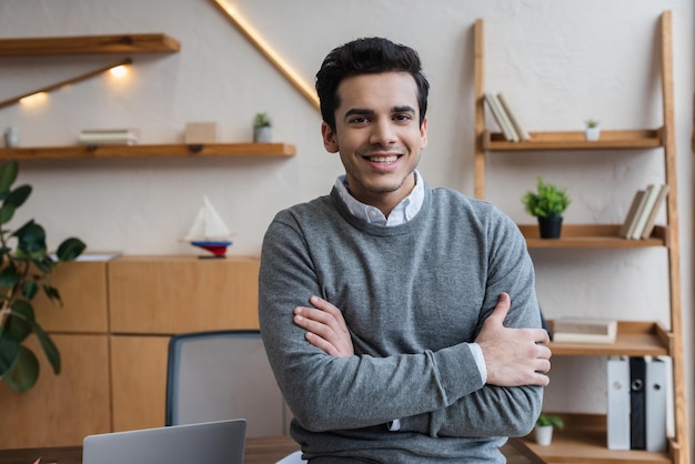 Businessman with crossed arms smiling and looking at camera in office